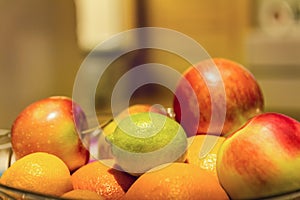 Fruit basket with orange, apple and lime with blurred background and copy space.