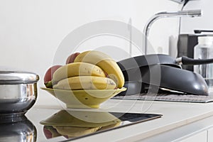 fruit bowl with bananas in the kitchen, next to the hot plate, we see its reflection in it