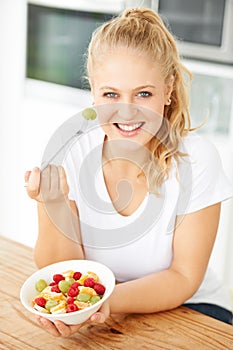 Fruit, bowl and portrait of woman eating healthy lunch or breakfast meal or diet in the morning in her home kitchen