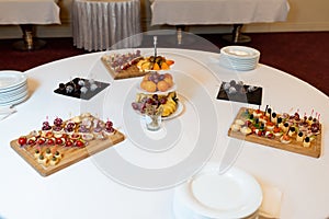 Fruit canapes and sweets lie on a white table