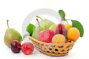 Fruit composition - wicker wooden basket with whole ripe fruits - pears, plums, apricots and apples on a white background