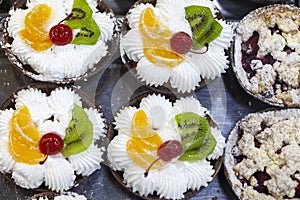 Fruit creamy cakes with canned cherry, orange and kiwi topping.