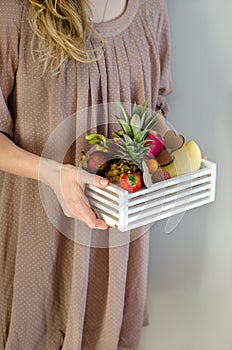 Fruit creative serving. Woman`s hands holding a wooden box with exotic fruits. Romantic gift. Passion fruit, strawberries,