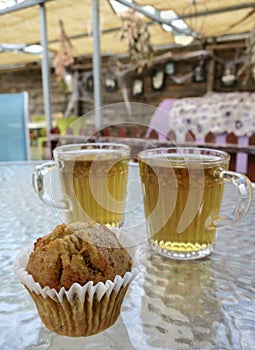 Fruit cupcake muffin with cups of herbal tea on a glass table at an eco farm in Cyprus