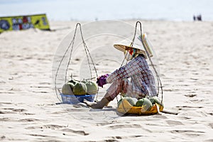 Fruit and drink seller sit on sandy beach in Nam Tien, Vietnam
