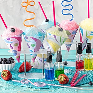 Fruit flavoured icy snow cones with different flavour syrups in front. photo