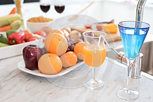 Fruit and fruit juice on marble counter in kitchen room. Apple and orange juice and vegetable on table. Food and drinks concept.