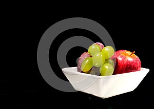 Fruit grape apple plum on a white plate