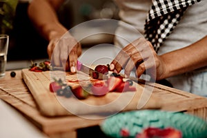 Fruit, hands and knife with person in kitchen of home for diet, health or nutrition closeup. Cooking, food or strawberry