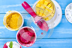 Fruit ice cream in buckets, on a blue wooden background and mango. Flut lay