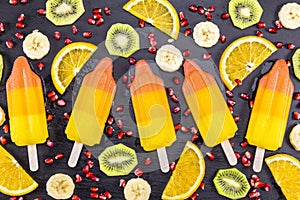 Fruit popsicles ice cream with sliced fruits on black