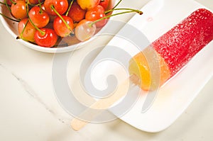 Fruit ice and sweet cherry in a white bowl/fruit ice and sweet cherry on a white marble background. Top view
