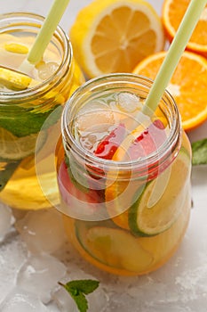 Fruit ice tea and ginger herbal ice tea with mint in glass jars, white background, copy space. Summer refreshing drink concept.