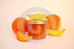 Fruit jam. A closed glass jar of jam, sliced peaches and whole fruit isolated on a white background.