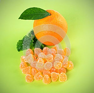 Ruit jelly  candies ,orange with leaf, spice, on a green