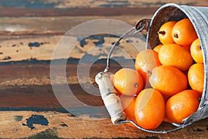 Fruit Jocote (Red Mombin, Purple Mombin, Hog Plum, Ciruela Huesito, Sineguela, Siriguela) in bucket on wooden table with copy sp photo