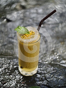 fruit juice, fruit smoothie, fruit juice, fruit juice in glass Placed on a rock near the waterfall