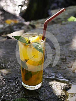 fruit juice, fruit smoothie, fruit juice, fruit juice in glass Placed on a rock near the waterfall