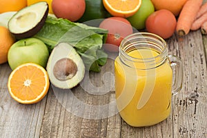 Fruit juice in the glass jar. Green background, wooden table. Fresh vegetables and fruits - avocado, apple, tomatoes. . Healthy,