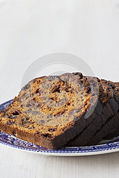 Fruit loaf cake sliced on a decorated blue and white plate.