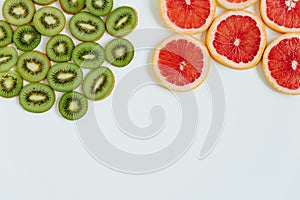 Fruit mix of kiwi and grapefruit slices on the white background. Top view. Minimal colourful trend style. Copy space