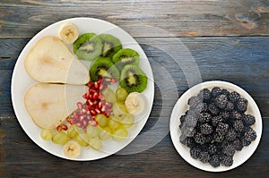 Fruit mix pear, kiwi, grapes, banana, pomegranate on a wooden background