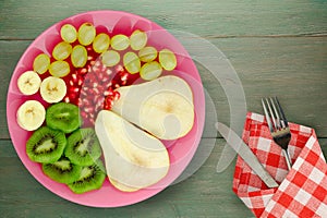 Fruit mix pear, kiwi, grapes, banana, pomegranate on a wooden background