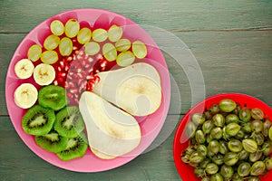 Fruit mix pear, kiwi, grapes, banana, pomegranate on a wooden background