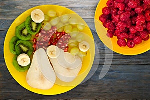 Fruit mix pear, kiwi, grapes, banana, pomegranate on a wooden background