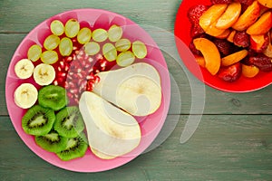 Fruit mix pear, kiwi, grapes, banana, pomegranate on a wooden background