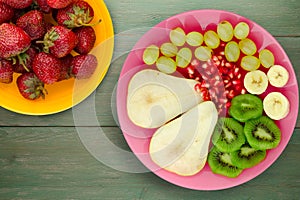 Fruit mix pear, kiwi, grapes, banana, pomegranate on a wooden background