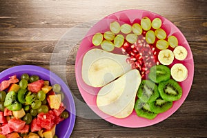 Fruit mix pear, kiwi, grapes, banana, pomegranate on a wooden background