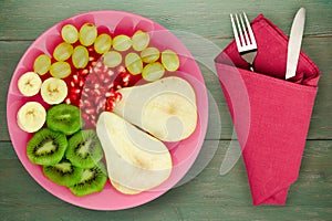 Fruit mix pear, kiwi, grapes, banana, pomegranate on a wooden background