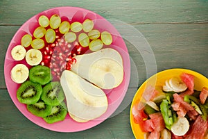 Fruit mix pear, kiwi, grapes, banana, pomegranate on a wooden background