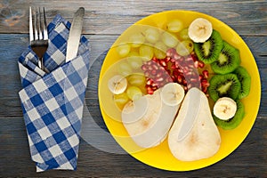 Fruit mix pear, kiwi, grapes, banana, pomegranate on a wooden background