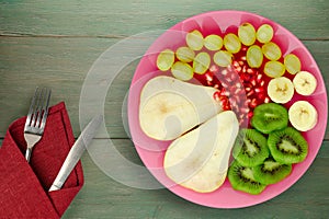 Fruit mix pear, kiwi, grapes, banana, pomegranate on a wooden background