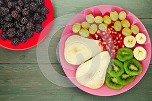 Fruit mix pear, kiwi, grapes, banana, pomegranate on a wooden background