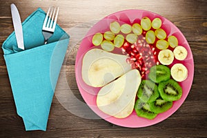 Fruit mix pear, kiwi, grapes, banana, pomegranate on a wooden background