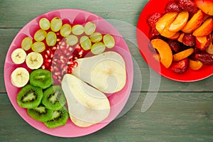 Fruit mix pear, kiwi, grapes, banana, pomegranate on a wooden background. fruit on a plate