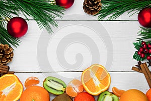 Fruit orange, tangerine and kiwifruit. Branch christmas tree and red ball with cone and cinnamon sticks on white wooden vintage ba