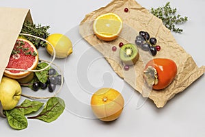 Fruit in paper bag. Persimmon, kiwi and orange on paper