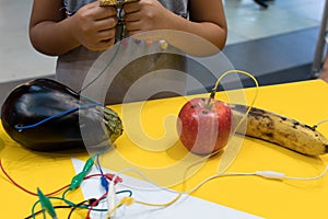 Fruit piano with kids. STEM education activity allow kids to play music with fruit and vegetables. Microcontroller converts keys