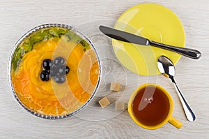 Fruit pie in baking form, saucer, knife, tea, lumpy sugar