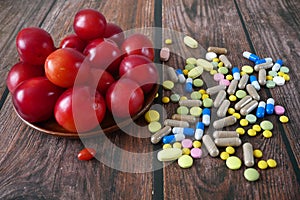 Fruit and pills, vitamin supplements with on wooden background. Healthy lifestyle, diet concept