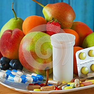 Fruit and pills, vitamin supplements with on wooden background. Healthy lifestyle, diet concept