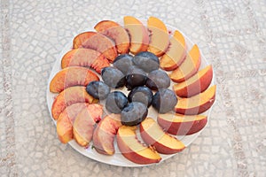 Fruit platter with fresh damson plums and peaches, on an old table