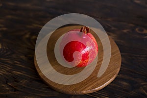 A fruit of pomegranate on a dark brown background.