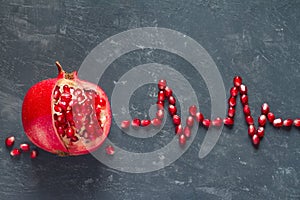 Fruit pomegranate and ECG cardiogram from pomegranate seeds, healthy heart diet concept abstract