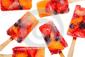 Fruit popsicles, homemade fruit ice lolly of various fruits with the addition of citrus lemonade on a black background, top view.