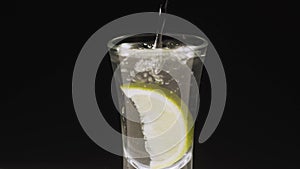 The fruit is poured into the water. Vodka is poured into a glass. Vodka and lime.